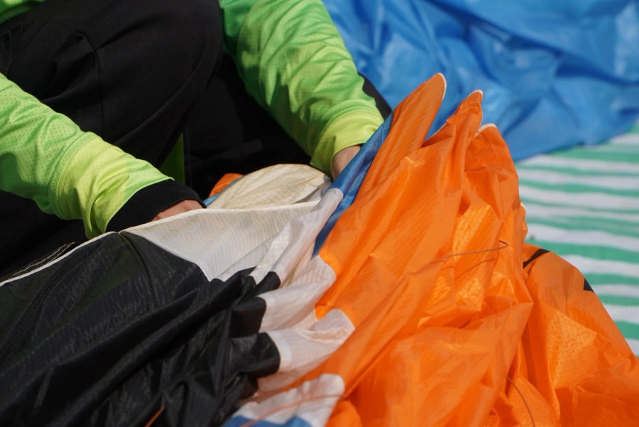 Sau lượt thi đấu, các phi công gấp gọn dù lượn để tiếp tục lượt thi đấu tiếp theo. ẢNH ĐỨC NHẬT