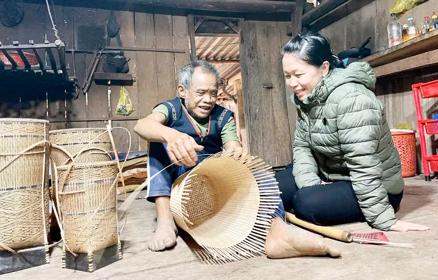 Chị Trần Thị Bích Ngọc trò chuyện, động viên nghệ nhân Đinh Bi gìn giữ, bảo tồn nghề đan lát. Ảnh: Phương Duyên