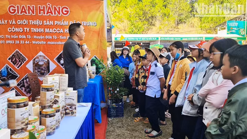 Các em học sinh trường Tiểu học Kim Đồng, xã Đăk Pék, huyện Đăk Glei tham quan, tìm hiểu các sản phẩm làm từ hạt macca.