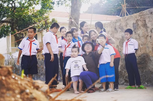 Phóng viên Phạm Thu Ngân chụp hình lưu niệm cùng các em học sinh ở Hòn Chuối. Ảnh Thanh Niên