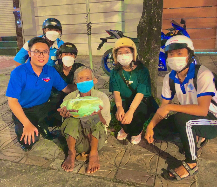 Nhân (mặc áo Đoàn) đi tặng gạo cho người có hoàn cảnh khó khăn. Ảnh: THANH DUY