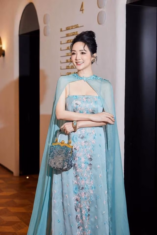 Chiếc đầm thiết kế tông xanh ngọc trang trí bởi các đường thêu tinh tế kết hợp với chiếc túi xách và trang sức cùng màu khiến người đẹp không chỉ quý phái, sang trọng mà còn rất trẻ trung và quyến rũ. Ảnh FACEBOOK NV