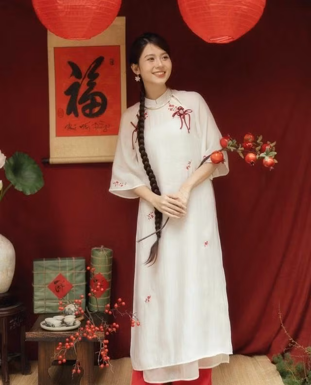 Giữa những nốt nhạc đỏ, hồng, vàng thì màu trắng của mẫu áo dài này như một âm luyến dịu dàng của bản giao hưởng mùa xuân. Quyện trong sức sống của vạn vật đất trời, thiết kế mang đến sự dịu dàng, thanh tao tới khung cảnh thiên nhiên đang nở rộ. Nếu nàng đang tìm một tông màu tạo nét trong trẻo cho năm mới thì đây chính là chiếc áo dài mà bạn đang tìm kiếm