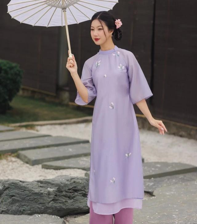 Tết đến, xuân sang, vạn vật trở mình thành bữa tiệc đầy náo nhiệt của âm thanh và ánh sáng. Cỏ cây hoa lá dần chuyển mình khoe sắc, đường phố thêm tấp nập tiếng người ta chúc tụng, những ánh nắng vàng của mùa xuân cũng dịu dàng bao phủ đất trời. Thế rồi, những tà áo dài chợt đến và mang theo một mảnh màu tím vừa vấn vương, vừa đượm tình khó tả. Chúng đẹp như một bức họa, với những nhành hoa trắng thêu truyền thống tỉ mỉ trên nền tím mơ màng Tết đến, xuân sang, vạn vật trở mình thành bữa tiệc đầy náo nhiệt của âm thanh và ánh sáng. Cỏ cây hoa lá dần chuyển mình khoe sắc, đường phố thêm tấp nập tiếng người ta chúc tụng, những ánh nắng vàng của mùa xuân cũng dịu dàng bao phủ đất trời. Thế rồi, những tà áo dài chợt đến và mang theo một mảnh màu tím vừa vấn vương, vừa đượm tình khó tả. Chúng đẹp như một bức họa, với những nhành hoa trắng thêu truyền thống tỉ mỉ trên nền tím mơ màng