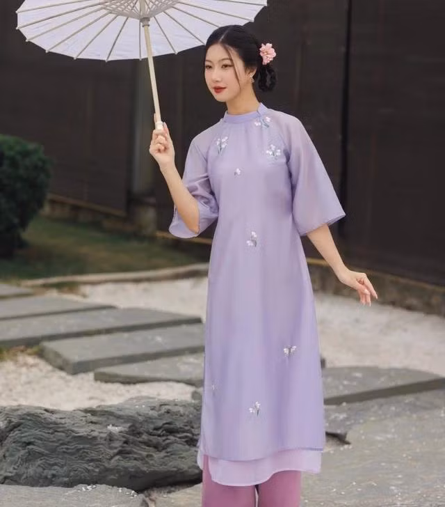 Tết đến, xuân sang, vạn vật trở mình thành bữa tiệc đầy náo nhiệt của âm thanh và ánh sáng. Cỏ cây hoa lá dần chuyển mình khoe sắc, đường phố thêm tấp nập tiếng người ta chúc tụng, những ánh nắng vàng của mùa xuân cũng dịu dàng bao phủ đất trời. Thế rồi, những tà áo dài chợt đến và mang theo một mảnh màu tím vừa vấn vương, vừa đượm tình khó tả. Chúng đẹp như một bức họa, với những nhành hoa trắng thêu truyền thống tỉ mỉ trên nền tím mơ màng Tết đến, xuân sang, vạn vật trở mình thành bữa tiệc đầy náo nhiệt của âm thanh và ánh sáng. Cỏ cây hoa lá dần chuyển mình khoe sắc, đường phố thêm tấp nập tiếng người ta chúc tụng, những ánh nắng vàng của mùa xuân cũng dịu dàng bao phủ đất trời. Thế rồi, những tà áo dài chợt đến và mang theo một mảnh màu tím vừa vấn vương, vừa đượm tình khó tả. Chúng đẹp như một bức họa, với những nhành hoa trắng thêu truyền thống tỉ mỉ trên nền tím mơ màng