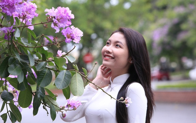 Một bạn gái trẻ trong tà áo dài bên hoa bằng lăng tím Một bạn gái trẻ trong tà áo dài bên hoa bằng lăng tím