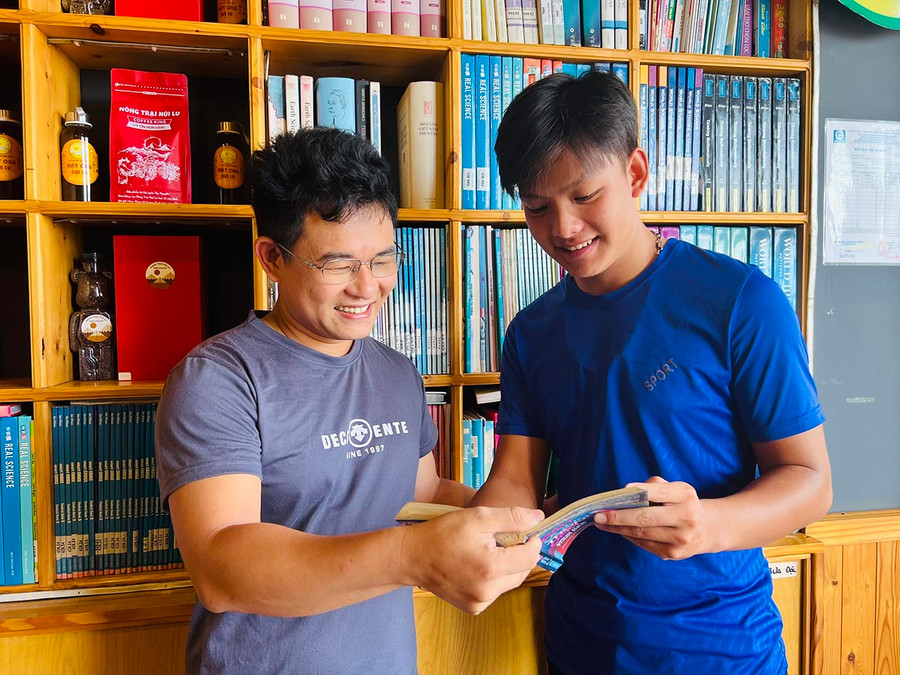 Anh Vũ Văn Tuyền (bìa trái) giới thiệu cuốn sách hay cho em Hồ Viết Kin. Ảnh: M.N