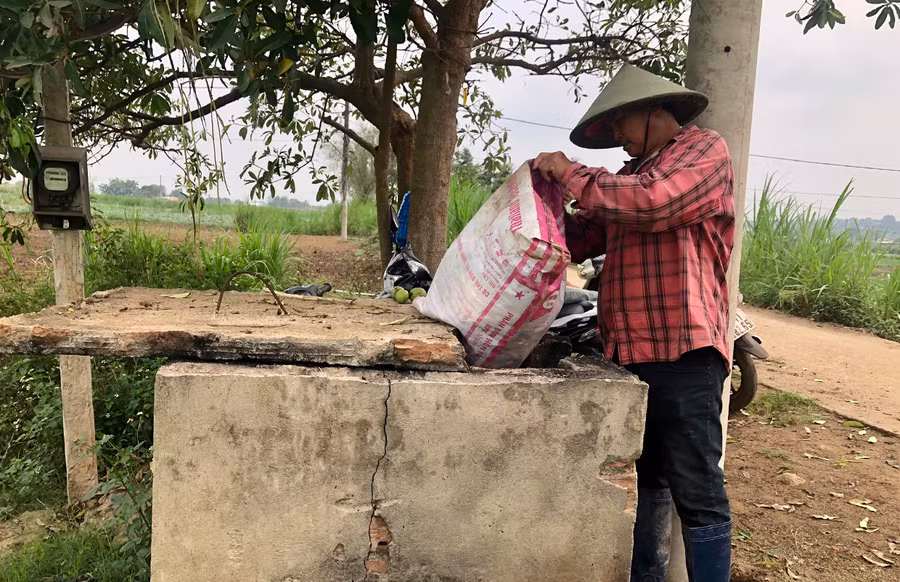 Ông Nguyễn Hoàng Trang (thôn 4, xã An Phú) đổ bao bì thuốc BVTV vào bể chứa. Ảnh: Lê Nam