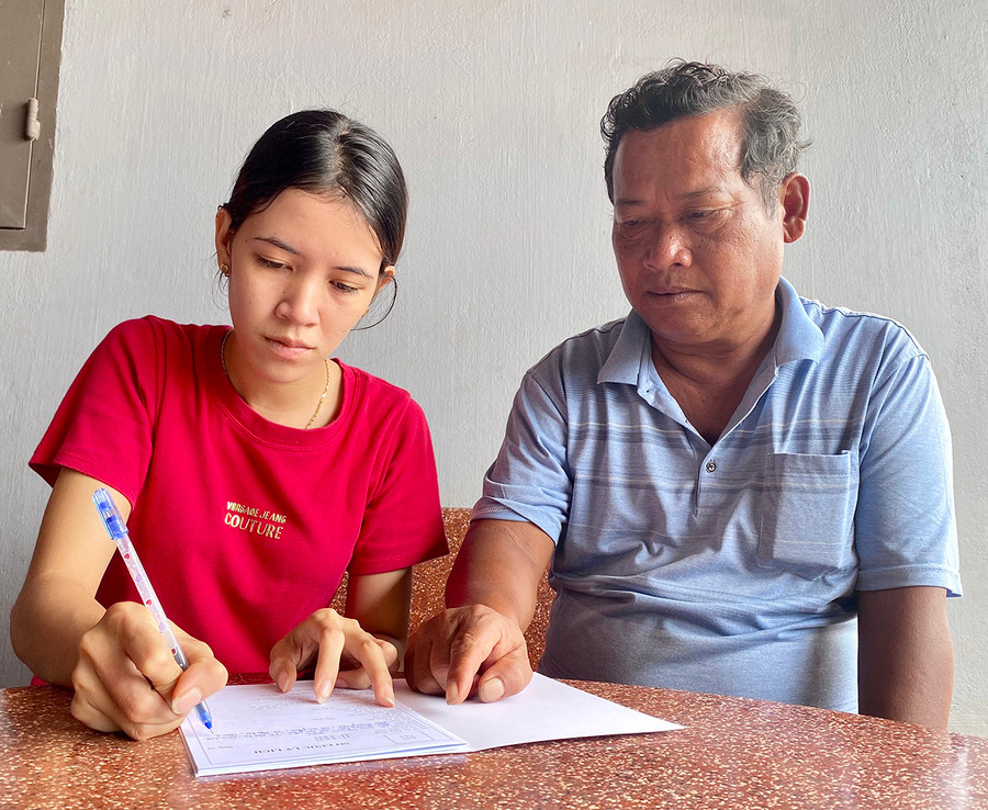 Ông Y Băn-Phó Bí thư Chi bộ làng Thung Dôr (xã An Phú) hướng dẫn chị H&apos;Len viết lý lịch xin vào Đảng. Ảnh: Mộc Trà