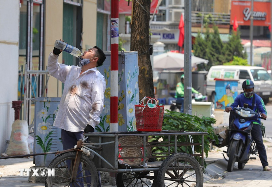 Một người dân bổ sung thêm nước khi phải di chuyển dưới cái nắng, nóng trên 40 độ C. (Ảnh: Hoàng Hiếu/TTXVN)
