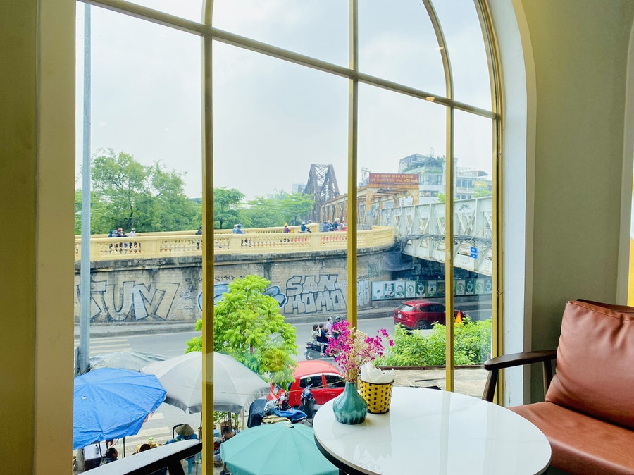 Cầu Long Biên ẩn hiện qua ô cửa kính của quán. Ngồi góc này vào buổi chiều hoàng hôn buông sẽ rất đẹp. Bạn có thể chiêm ngưỡng mặt trời đỏ rực nằm ngay trên nóc cầu Long Biên, cảnh tượng vô cùng lãng mạn. Cầu Long Biên ẩn hiện qua ô cửa kính của quán. Ngồi góc này vào buổi chiều hoàng hôn buông sẽ rất đẹp. Bạn có thể chiêm ngưỡng mặt trời đỏ rực nằm ngay trên nóc cầu Long Biên, cảnh tượng vô cùng lãng mạn.