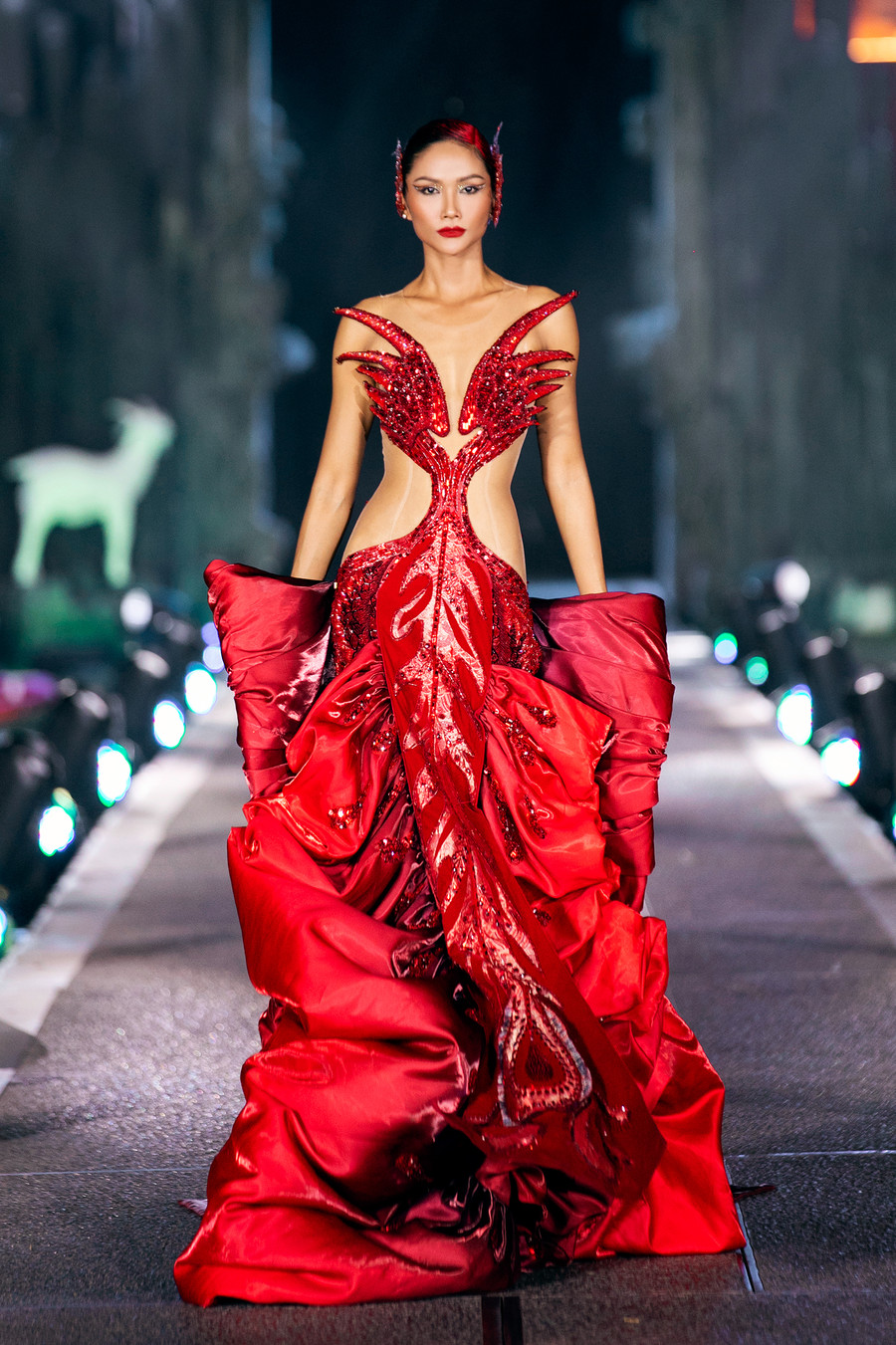 Đảm nhận vai trò kết màn cho Nguyệt hồi là Hoa hậu H&apos;Hen Niê. Cô diện váy đỏ với những đường cắt xẻ táo bạo, giúp tôn vóc dáng nóng bỏng. Người đẹp Ê Đê là gương mặt xuất hiện ở nhiều sự kiện thời trang nhờ kỹ năng trình diễn tốt. Ảnh: Team Kiếng Cận