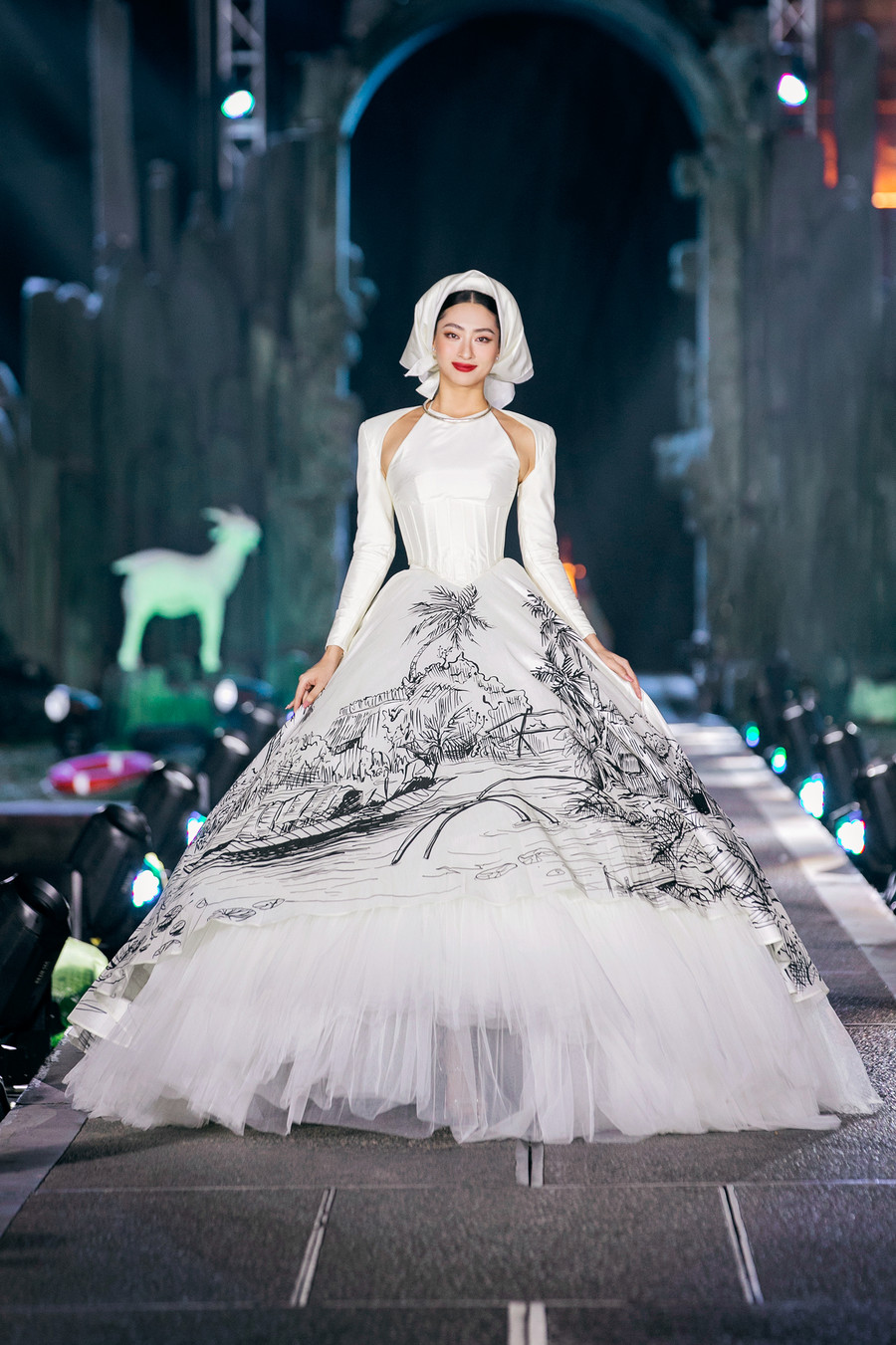 Lương Thùy Linh kết màn cho bộ sưu tập Kinh kỳ của Nguyễn Minh Công. Thiết kế lấy cảm hứng từ chiếc áo yếm, giúp tôn lên nhan sắc của người đẹp quê Cao Bằng. Chiều cao vượt trội cùng đôi chân dài giúp Miss World Vietnam 2019 nổi bật trên sàn diễn. Ảnh: Team Kiếng Cận
