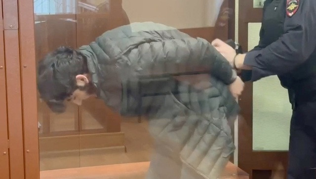 Nazrimad Lutfulloi, bị bắt trong quá trình điều tra vụ tấn công khu Crocus City Hall ở gần thủ đô Moscow vào tối 22.3, bị áp giải sau bức tường kính của khu dành cho các bị cáo trong phòng xử án ở Moscow, trong ảnh từ video được phát hành ngày 29.3. Ảnh: Reuters Nazrimad Lutfulloi, bị bắt trong quá trình điều tra vụ tấn công khu Crocus City Hall ở gần thủ đô Moscow vào tối 22.3, bị áp giải sau bức tường kính của khu dành cho các bị cáo trong phòng xử án ở Moscow, trong ảnh từ video được phát hành ngày 29.3. Ảnh: Reuters