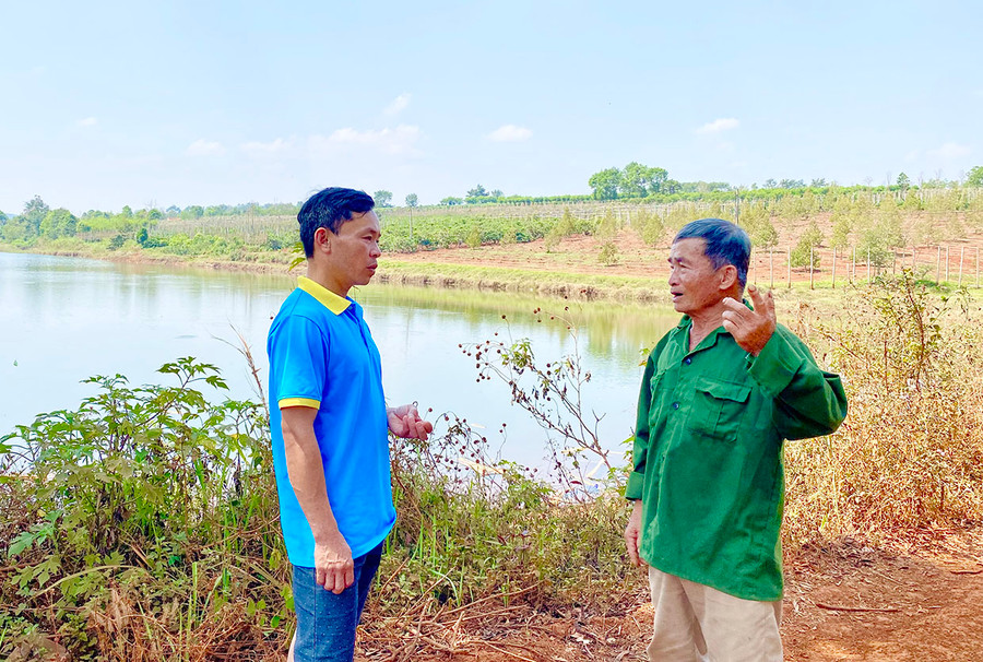 Ông Trần Đình Bông (bìa phải) bên “hồ ba Bông”-nguồn nước tưới cho hàng ngàn héc ta cà phê, sầu riêng ở khu vực này. Ảnh: H.D