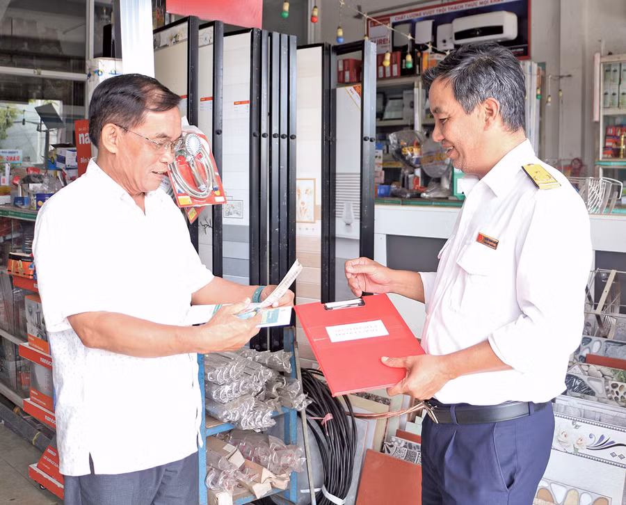 Cán bộ của Chi cục Thuế TP. Pleiku (bìa phải) hướng dẫn người dân sử dụng hóa đơn điện tử, nộp thuế điện tử. Ảnh: Q.T