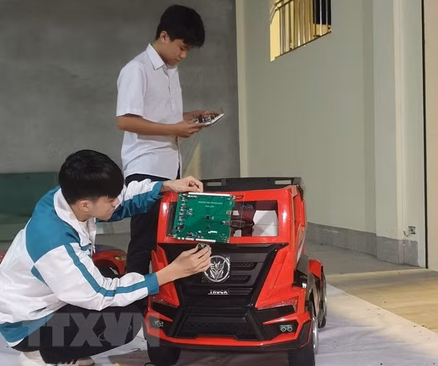 Em Phạm Đăng Minh (đứng) và Hoàng Văn Đồng nghiên cứu thực hiện đề tài. (Ảnh: Hải Yến/TTXVN)