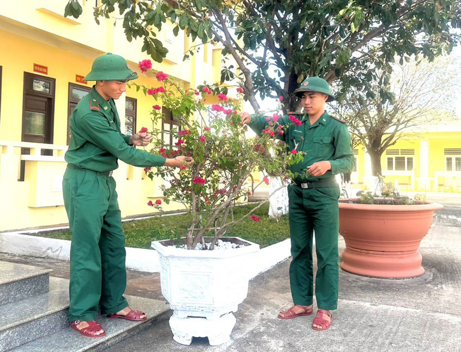 Chiến sĩ Trần Huỳnh Sơn (bìa phải) và chiến sĩ Rơ Mah Thanh chăm sóc cây cảnh trong khuôn viên đơn vị. Ảnh: P.D