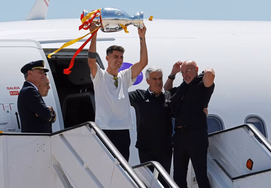 Đội trưởng Alvaro Morata nâng cao cúp vô địch ở cửa máy bay. Ảnh Reuters