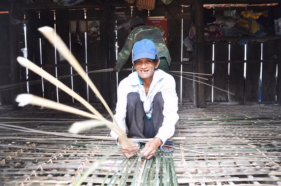 Ông Bro đan lớp trên cùng của sàn nhà bằng nan cây lồ ô. Ảnh: Nguyễn Anh Minh