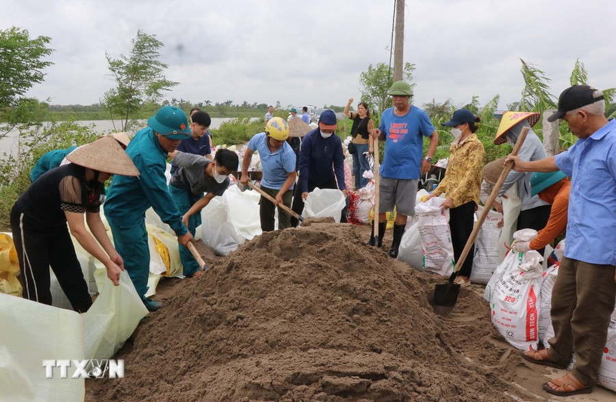 Người dân xã Long Châu (Yên Phong, Bắc Ninh) cùng chính quyền địa phương xử lý sự cố sụt, lún mặt đê tại bờ Ngũ Huyện Khê. (Ảnh: Thái Hùng/TTXVN)