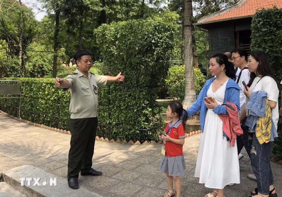 Anh Nguyễn Minh Hà, nhân viên bảo vệ Khu Di tích Nhà sàn Bác Hồ hướng dẫn khách tham quan. (Ảnh: Phương Lan/TTXVN)