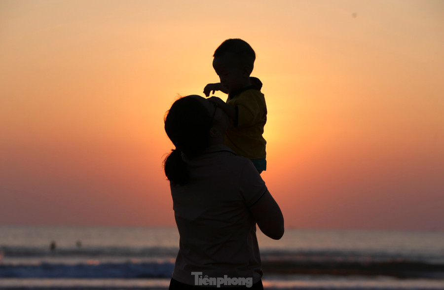 “Lần đầu tiên cùng gia đình đến biển Xuân Thành, tôi cố gắng thức dậy sớm để ngắm bình minh, cảm nhận không khí tuyệt vời nhất”, Hoài Thường (17 tuổi, trú TP Hà Tĩnh) chia sẻ. Dưới ánh mặt trời ló rạng, người mẹ trao nụ hôn và tình yêu thương đến con trai.