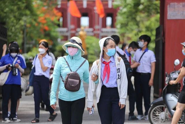 Phụ huynh lẫn học sinh bịt kín để chống nắng nóng. Ảnh: THANH NIÊN