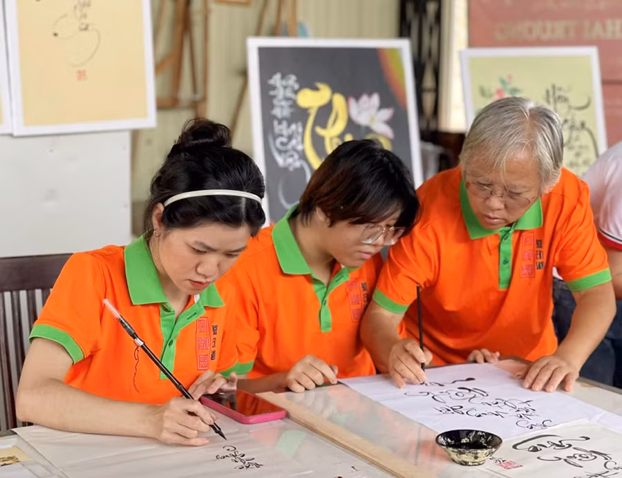 Chị Lê Thị Mỹ Tiên-Thành viên Câu lạc bộ Thư pháp chữ Việt Pleiku hướng dẫn các em viết thư pháp. Ảnh: P.D