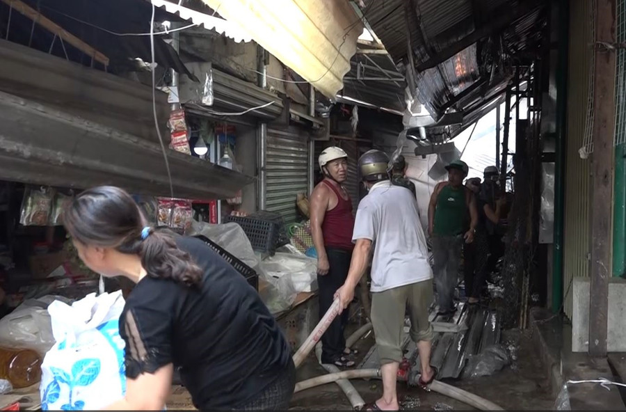 Tiểu thương bên trong chợ giúp nhau di chuyển đồ đạc, tránh thiệt hại. Ảnh: Bảo Trung