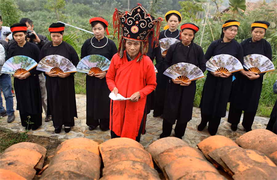 Thầy bụt và 12 cô gái tượng trưng cho 12 nàng Trăng làm lễ tại miếu thờ thổ công. (Nguồn: Báo Ảnh Việt Nam)