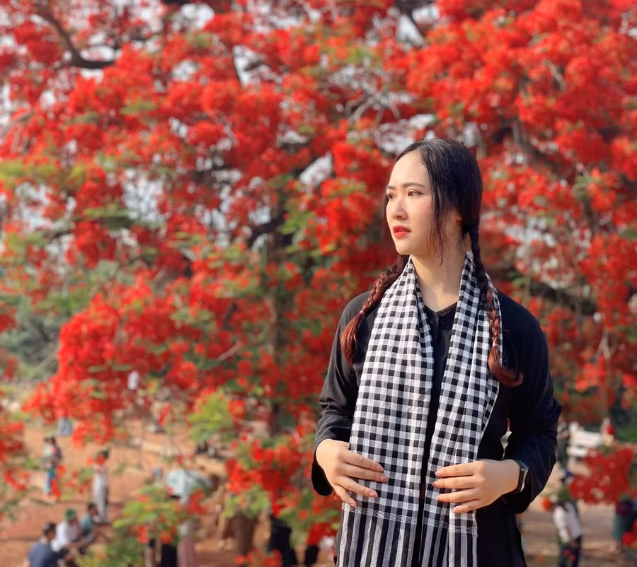 Trần Linh Ngọc trong trang phục áo bà ba, khăn rằn chụp hình với hoa phượng. Ảnh: NVCC