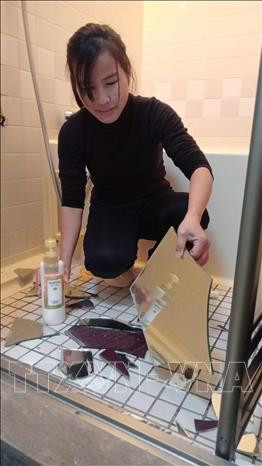 Chị Lê Thị Dậu - một lao động Việt Nam đang dọn dẹp vật dụng trong nhà bị hư hại do động đất. Ảnh: TTXVN