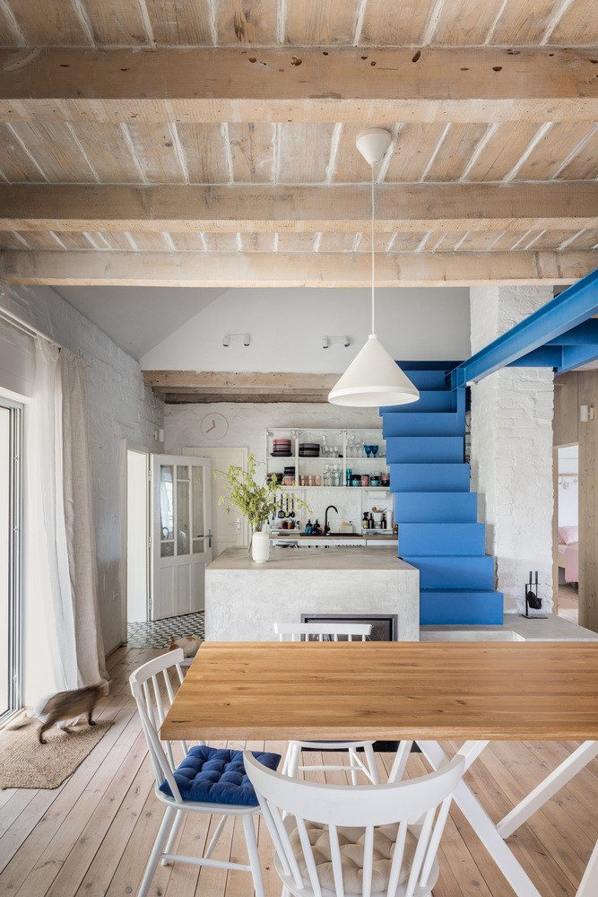 Ngôi nhà sử dụng màu sắc chủ đạo là trắng, kết hợp với nội thất bằng gỗ, kết hợp với chiếc cầu thang sắt màu xanh làm điểm nhấn.