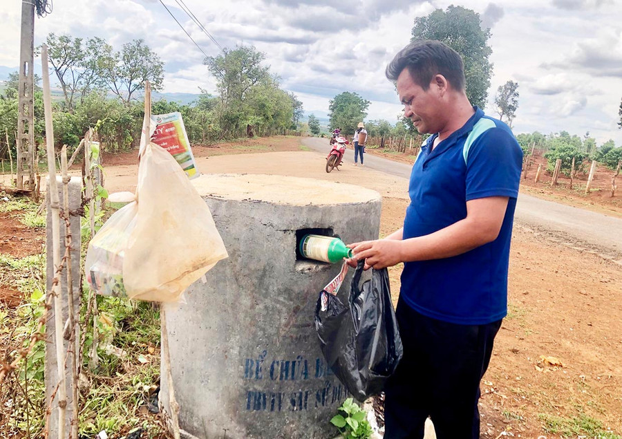Ông Rơ Châm Hưh (làng Kép, xã Ia Phí) bỏ chai thuốc bảo vệ thực vật sau khi sử dụng vào bể chứa chất thải nguy hại. Ảnh: G.H