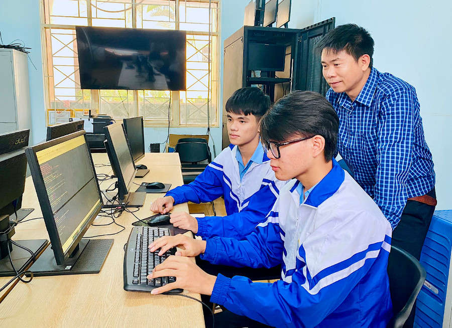 Hai em Đặng Quốc Cường (ngồi phía trong) và Lê Văn Trường tham gia bồi dưỡng kiến thức lập trình Tin học cùng giáo viên. Ảnh: Mộc Trà