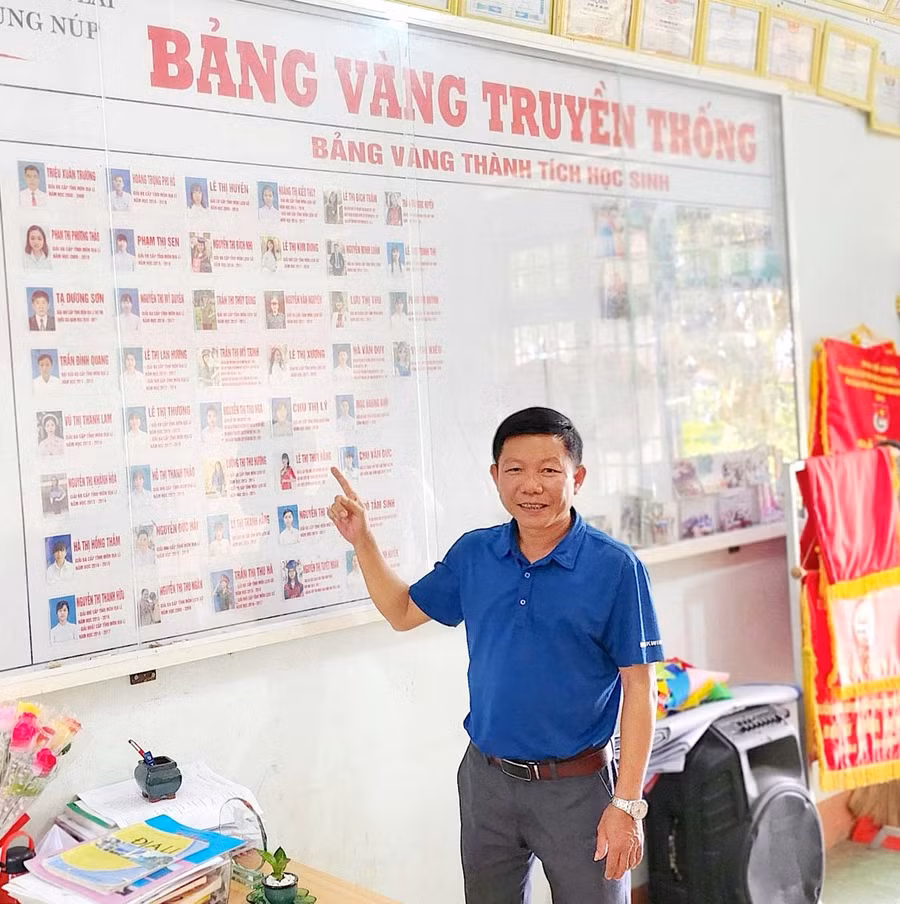 Thầy Lương Thế Hùng-Phó Hiệu trưởng Trường THPT Anh Hùng Núp bên bảng vàng thành tích của học sinh. Ảnh: H.T