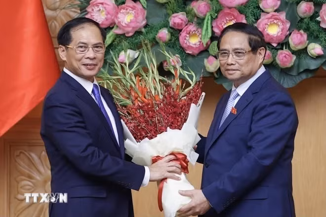 Thủ tướng Phạm Minh Chính tặng hoa chúc mừng tân Phó Thủ tướng, Bộ trưởng Bộ Ngoại giao Bùi Thanh Sơn. (Ảnh: Dương Giang/TTXVN)