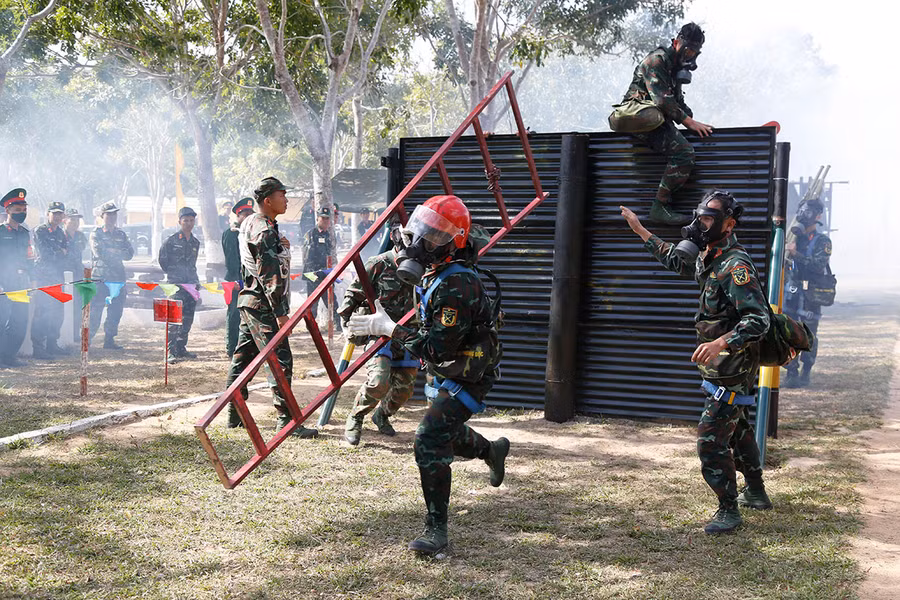 Các vận động viên thực hiện phần thi vượt chướng ngại vật trong điều kiện phải đeo thiết bị phòng độc. Ảnh: Vĩnh Hoàng Các vận động viên thực hiện phần thi vượt chướng ngại vật trong điều kiện phải đeo thiết bị phòng độc. Ảnh: Vĩnh Hoàng