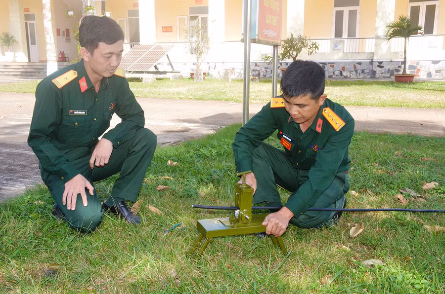 Thượng úy quân nhân chuyên nghiệp Nguyễn Văn Long (bìa phải) thực hành trên “Máy tách vỏ cáp quang”. Ảnh: V.H