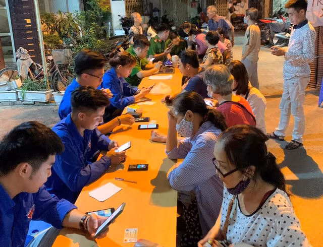 Đoàn viên, thanh niên hỗ trợ người dân cài đặt tài khoản định danh điện tử. Ảnh: NGUYỆT ÁNH