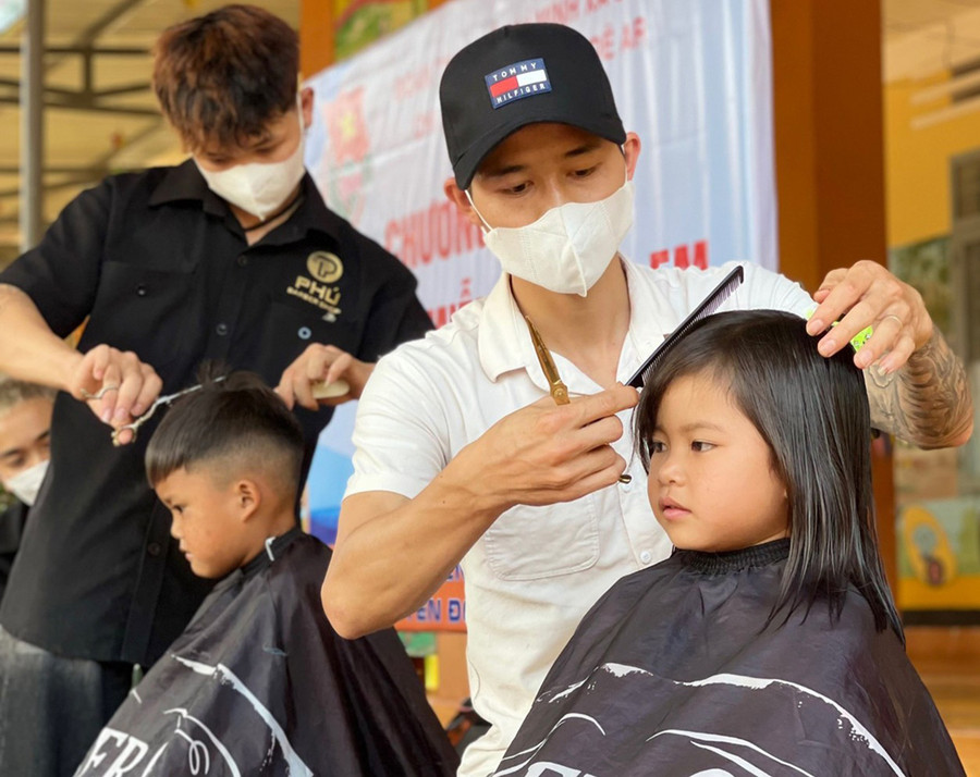 Anh Võ Đoàn Phú và cộng sự cắt tóc miễn phí cho các em học sinh Trường Mẫu giáo Đê Ar. Ảnh: Thiên Di