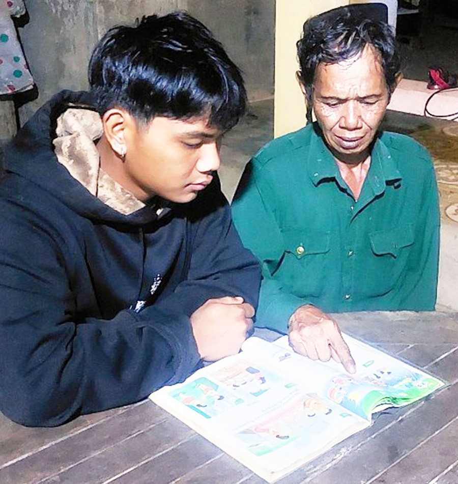 Tranh thủ giờ giải lao, ông Kpah Choan cùng con trai Kpah Vớt học bài. Ảnh: V.H Tranh thủ giờ giải lao, ông Kpah Choan cùng con trai Kpah Vớt học bài. Ảnh: V.H