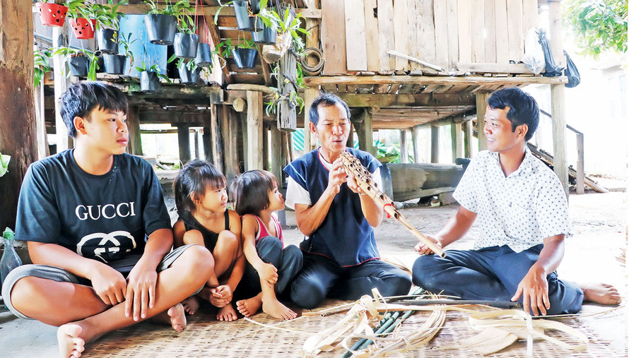 Ông Đinh Văn Uơng thổi đinh đuk cho con cháu nghe. Ảnh: N.M Ông Đinh Văn Uơng thổi đinh đuk cho con cháu nghe. Ảnh: N.M