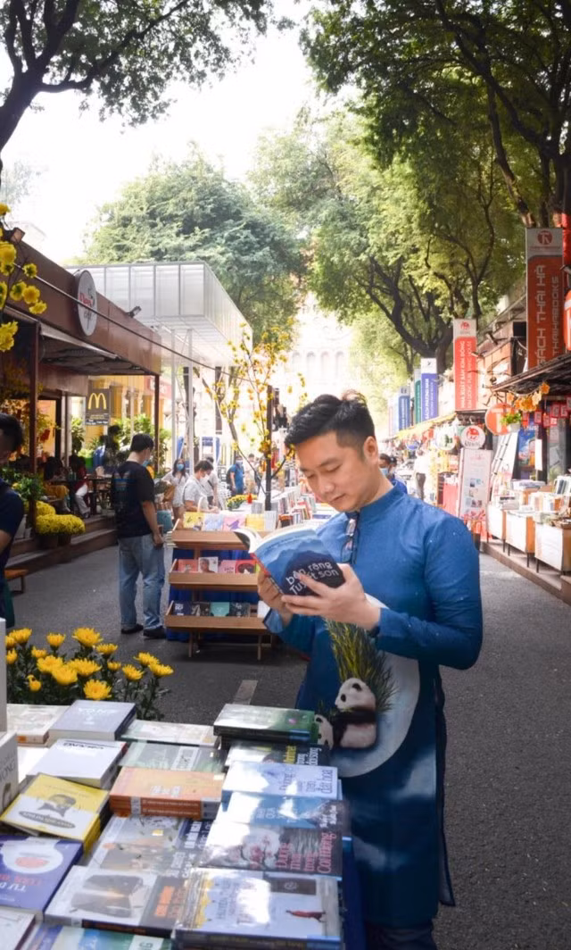 Anh Thế Hoàng (quê Hải Phòng) thường mặc áo dài ghé Đường sách TP HCM những ngày trước Tết để tìm chọn các ấn phẩm hay và lưu giữ hình ảnh kỷ niệm với bạn bè.