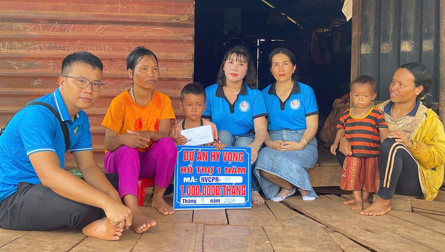 Anh Nguyễn Đắc Kiên Bình (bìa trái) cùng các thành viên dự án Hy vọng trao tiền hỗ trợ cho thiếu nhi khó khăn. Ảnh: Phan Lài