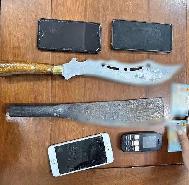 2 cây đao, mã tấu cùng điện thoại của nhóm côn đồ bị tạm giữ. Ảnh: NGUYỄN TÚ