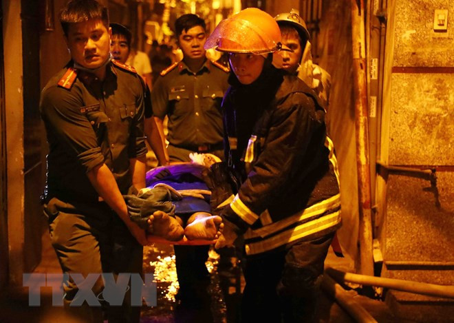 Lực lượng chức năng đưa nạn nhân ra khỏi hiện trường. (Ảnh: Phạm Kiên/TTXVN) Lực lượng chức năng đưa nạn nhân ra khỏi hiện trường. (Ảnh: Phạm Kiên/TTXVN)