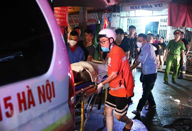 Lực lượng chức năng đưa nạn nhân ra khỏi hiện trường. (Ảnh: Phạm Kiên/TTXVN) Lực lượng chức năng đưa nạn nhân ra khỏi hiện trường. (Ảnh: Phạm Kiên/TTXVN)