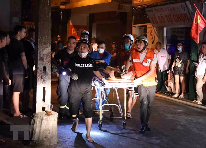 Lực lượng chức năng đưa các nạn nhân ra bên ngoài. (Ảnh: Phạm Kiên/TTXVN)